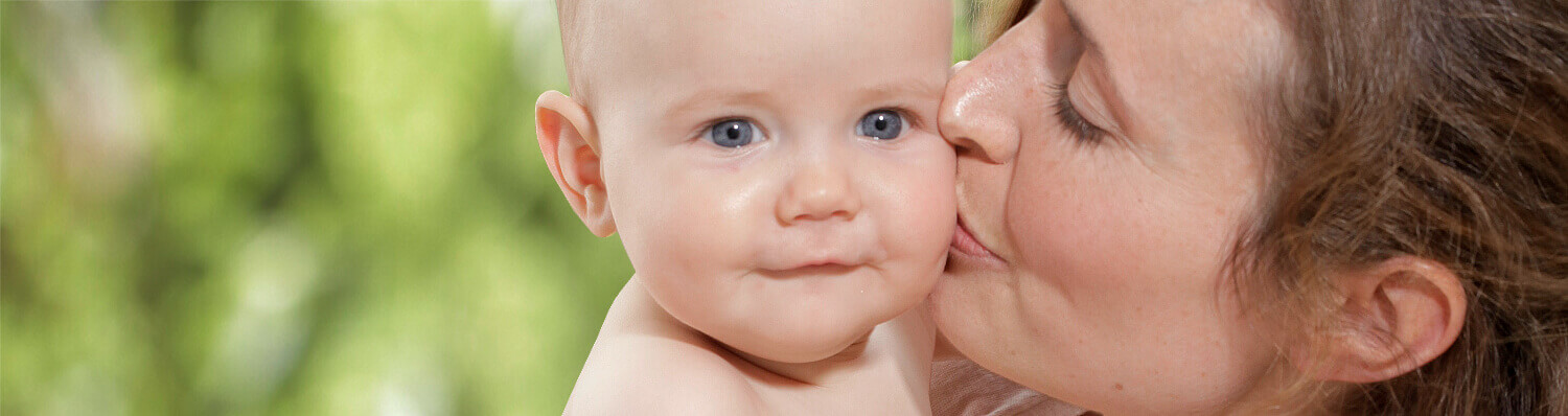 A woman is kissing a baby on the cheek.
