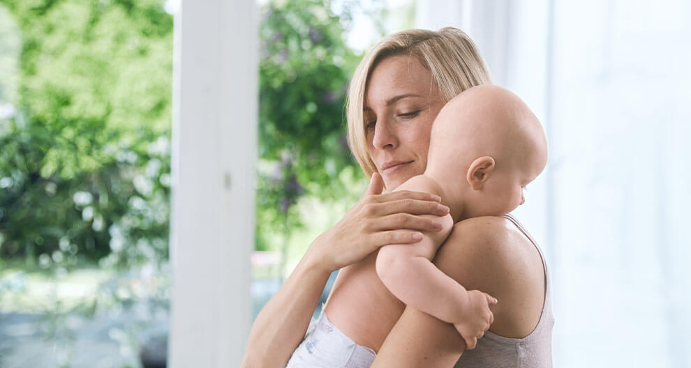 A woman is holding a baby close to her.