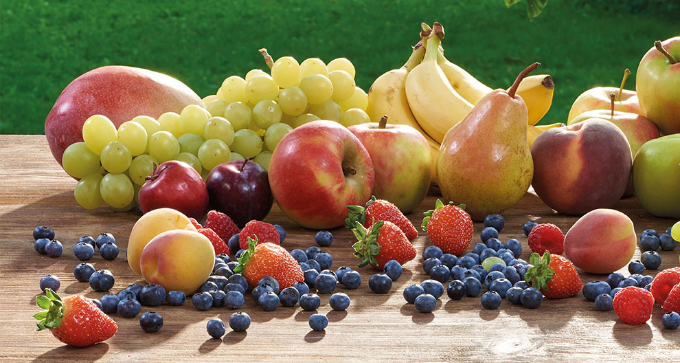 A variety of fresh fruits are displayed on a wooden surface.